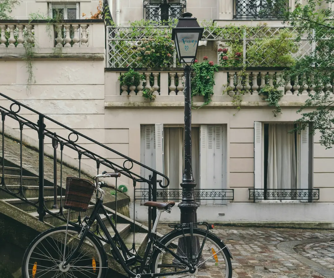 A bicycle by a lamp post under garden balconies in a French courtyard
